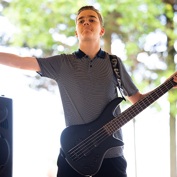 a man on stage with an electric guitar holds his arms out